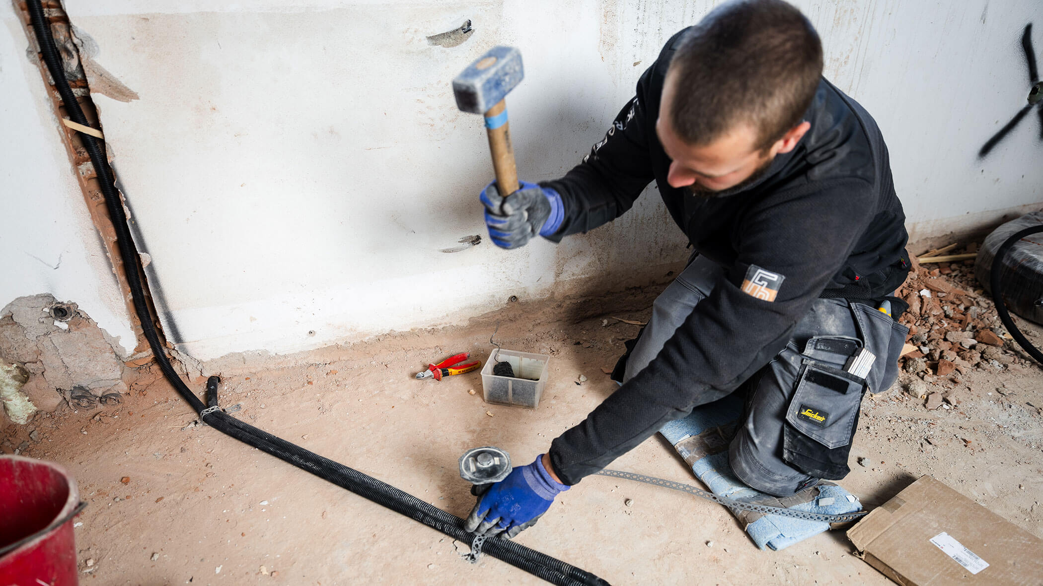 Elektriker fixiert die Rohre mit einem Hammer - Elektro Felderer