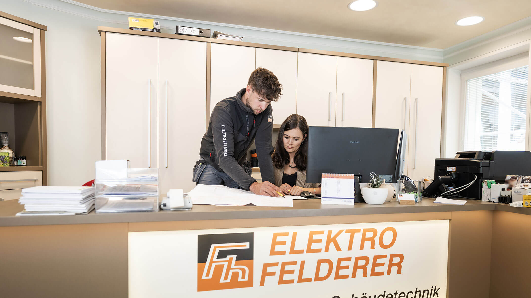 Elektriker erklärt der Bürofachkraft eine Zeichnung - Elektro Felderer