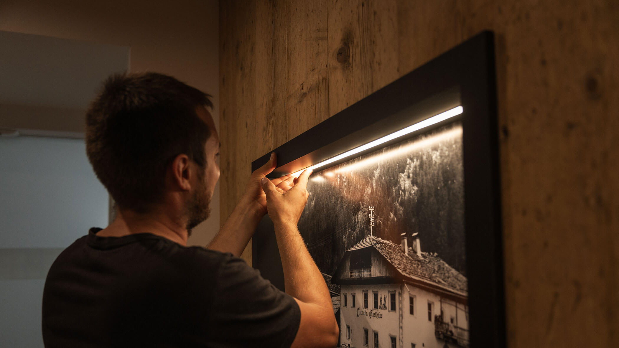 Elektriker montiert Lampe über einem Bild - Elektro Felderer