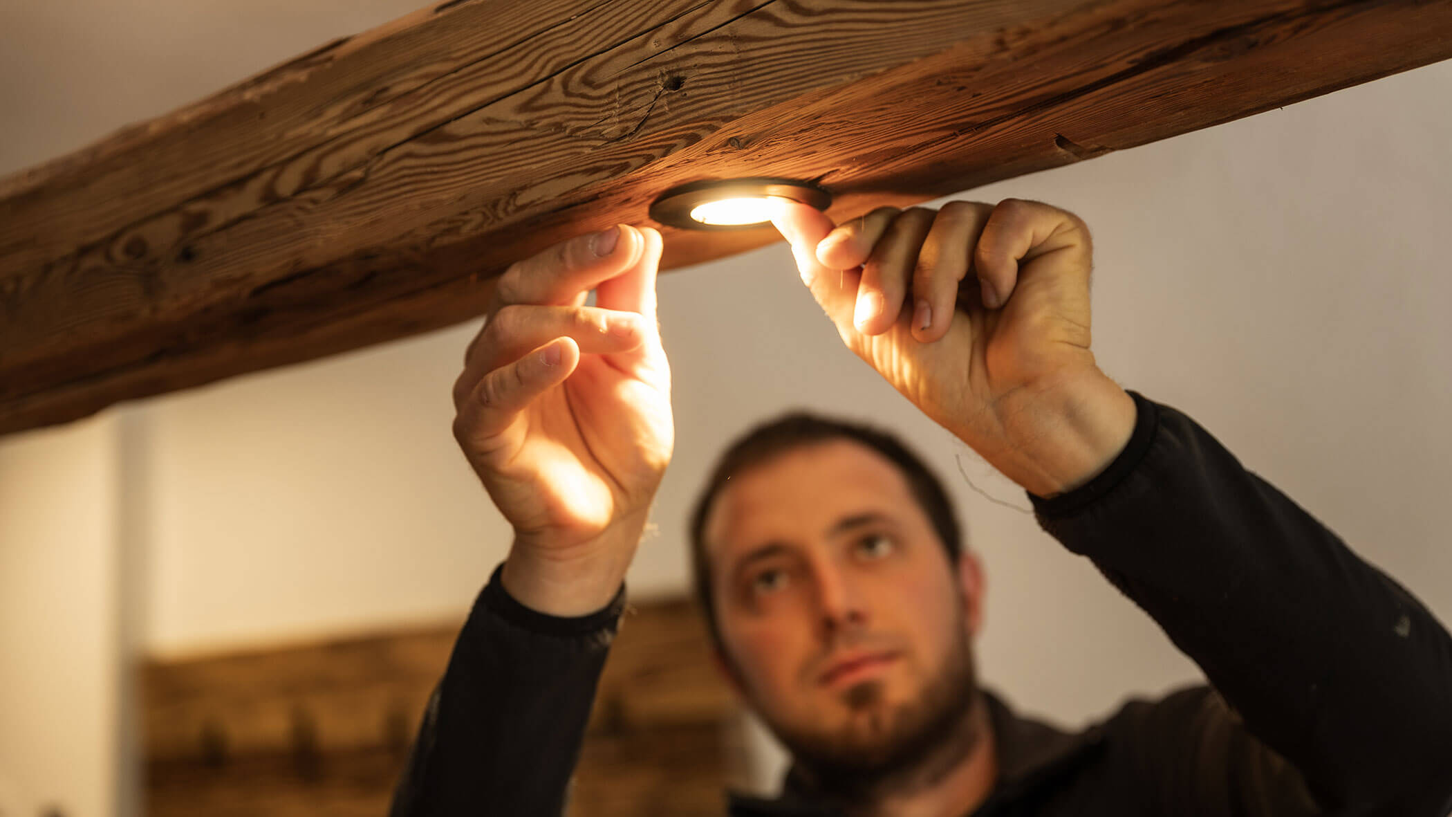 Elektriker montiert eine Lampe auf einen Holzpfosten - Elektro Felderer